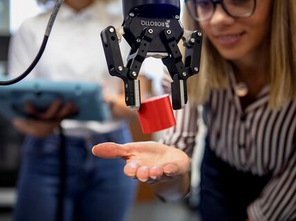 A robot dropping a red block on a woman’s palm. Image by: Terho Aalto 