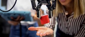 A robot dropping a red block on a woman’s palm. Image by: Terho Aalto 