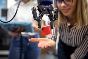 A robot dropping a red block on a woman’s palm. Image by: Terho Aalto 